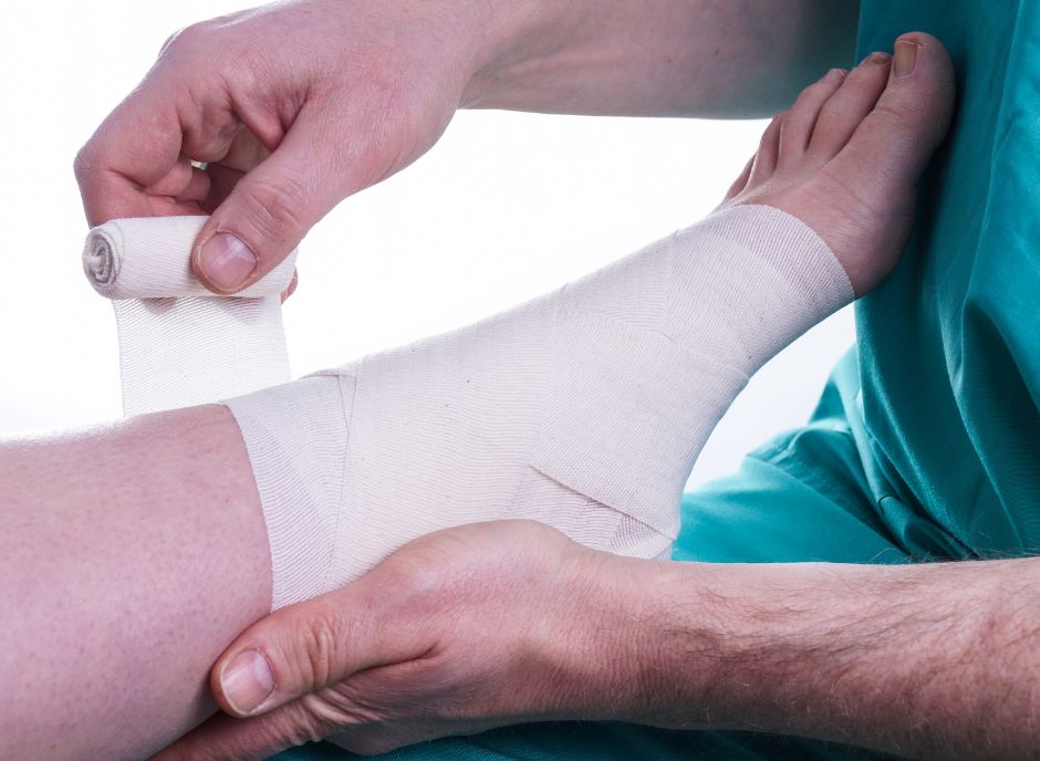 A healthcare provider applying a bandage to a patient's leg