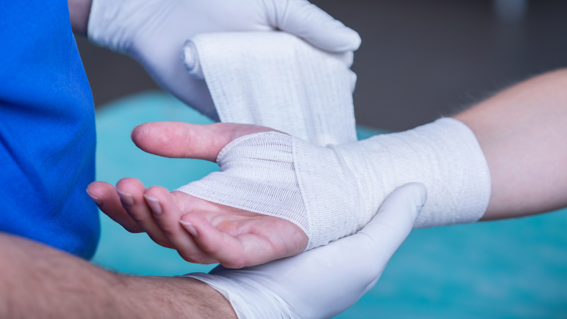 Healthcare professional wrapping a patient’s hand with a medical bandage for wound care.