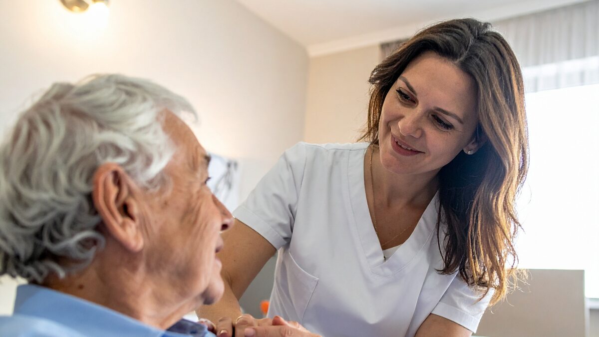 Healthcare professional providing chronic wound care at home for an elderly man.